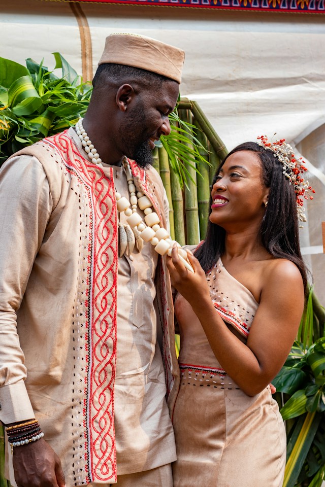 A couple in traditional attire smiling at each other during a cultural celebration